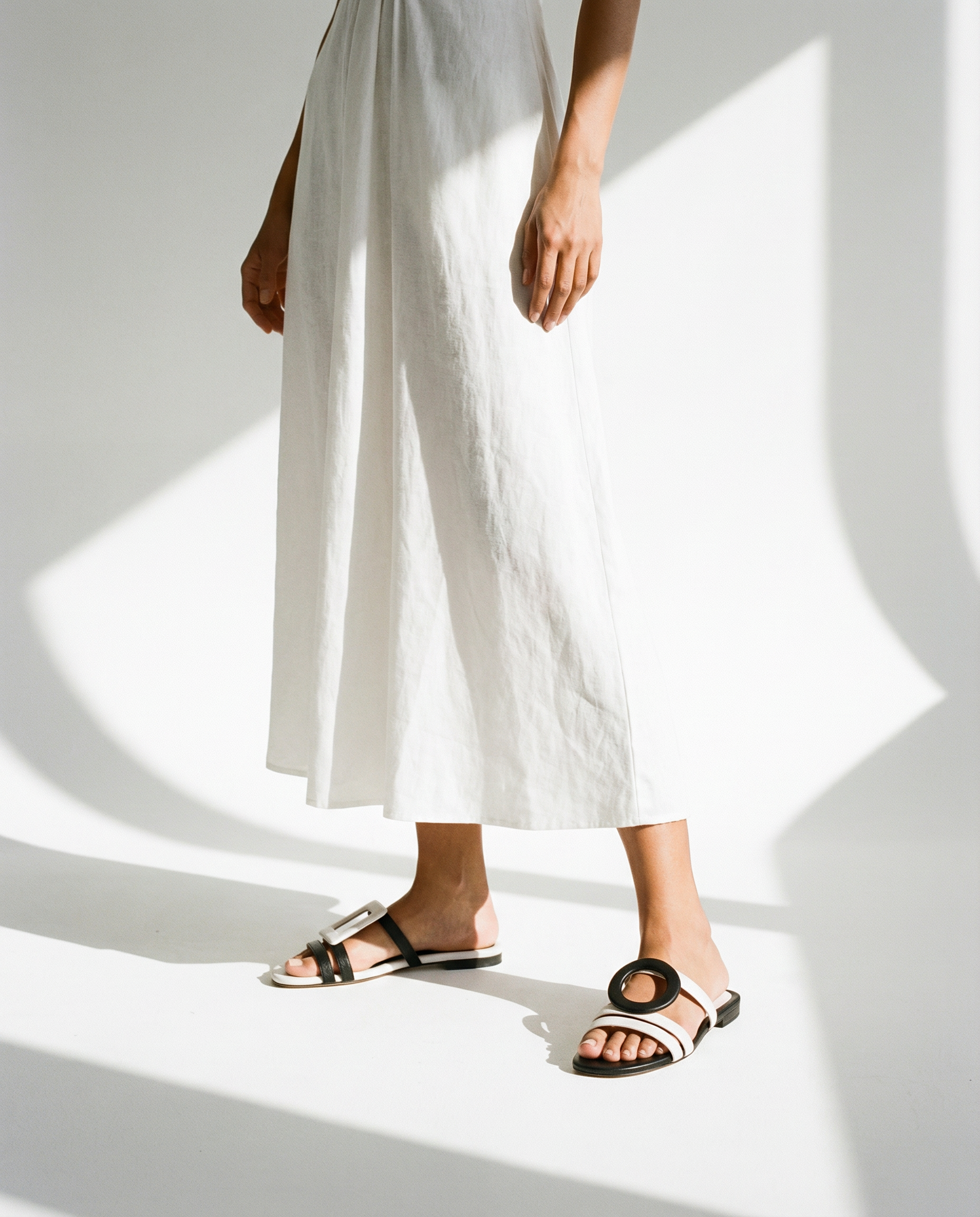 Person wearing white pants and two-tone sandals on a white background