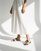 Person wearing white pants and two-tone sandals on a white background