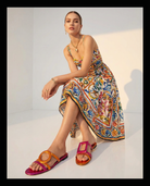 Woman wearing a colorful patterned dress and two-tone sandals on a white background