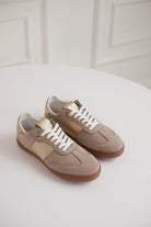 Pair of beige sneakers with white laces on a light background