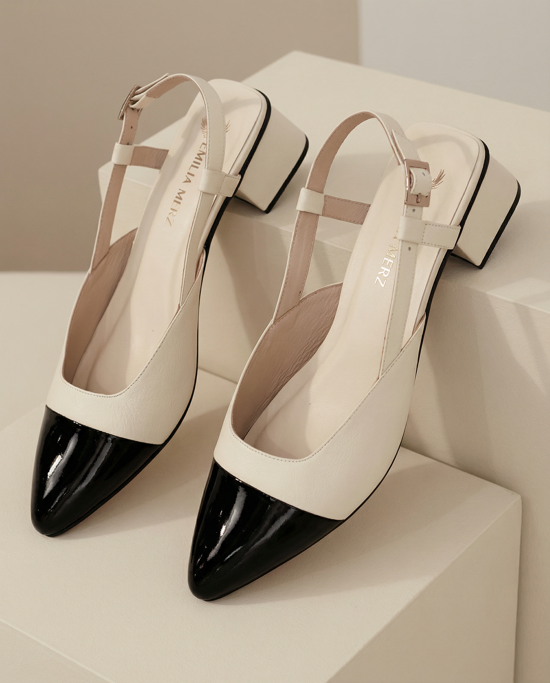 Pair of white and black pointed-toe shoes on a light surface