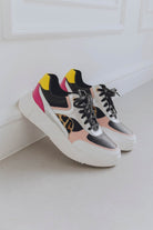 Pair of multicolor sneakers on a light wooden floor.