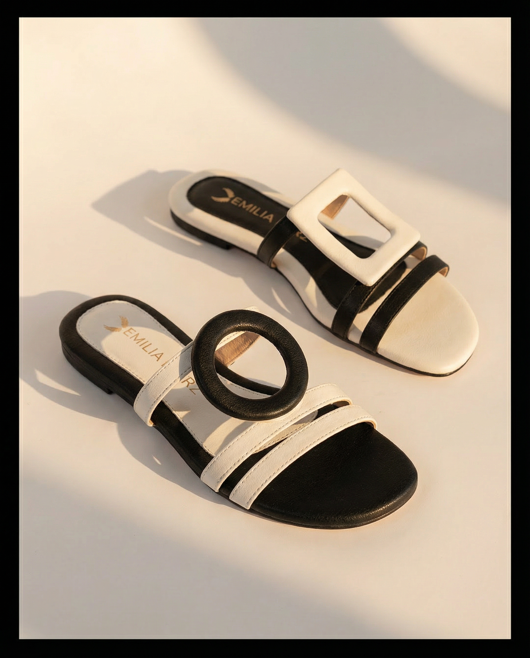 Black and white sandals with emilia merz logo on a light background