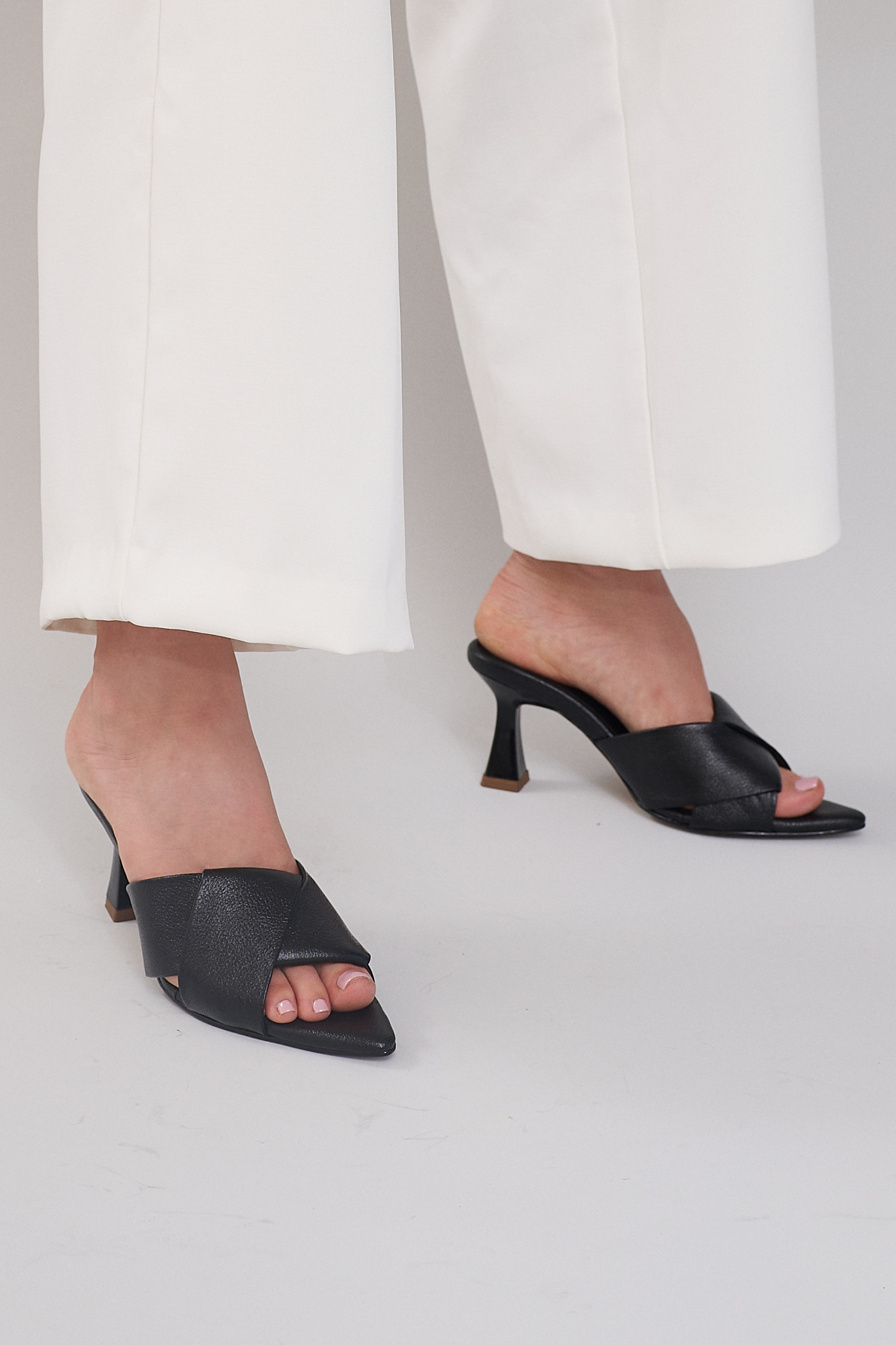 woman with white pants wearing black open toe heels from emilia merz